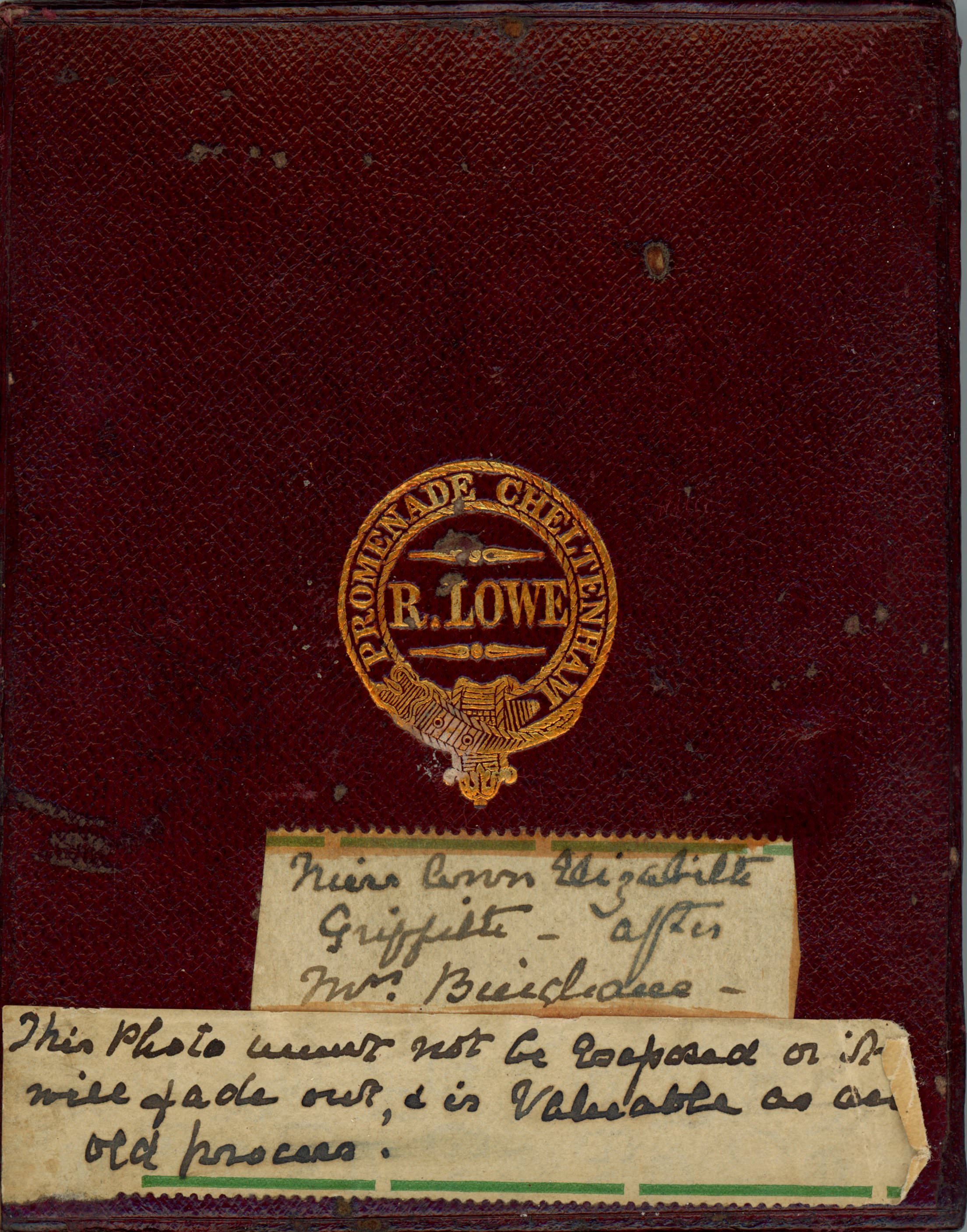 Case. A maroon-red leather case is embossed with a gold insignia. Two labels with handwriting are below. The first has the name of the sitter, and the second reads, “This Photo must not be exposed or it will fade out, and is valuable as an old process”.