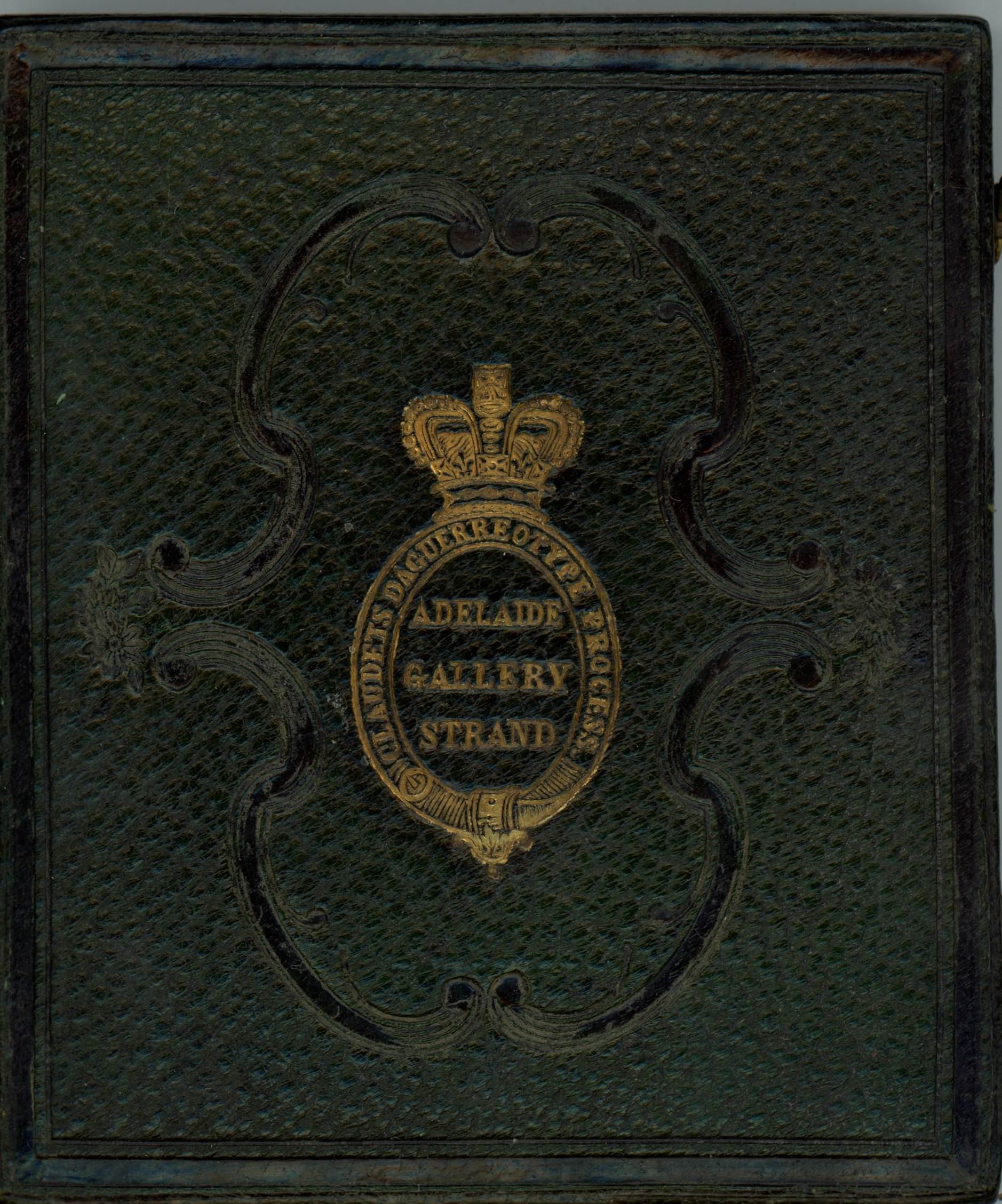 Forest-green leather case is stamped with a gold insignia of a crown over an oval cartouche. The insignia is surrounded by a tooled ornamental design of parentheses-shaped bands.